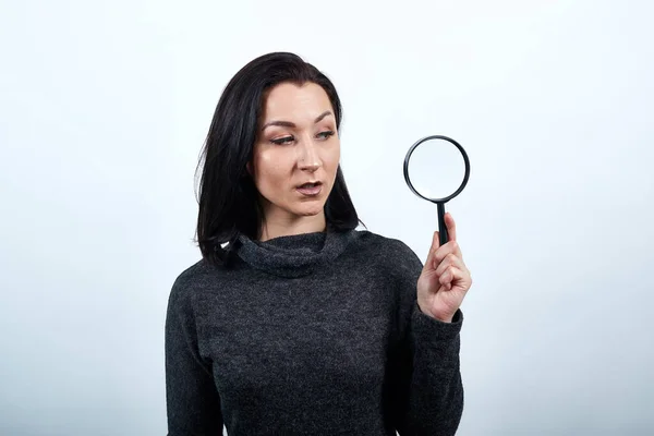 Una giovane donna caucasica delusa con in mano una lente d'ingrandimento. Stile di vita concetto — Foto Stock