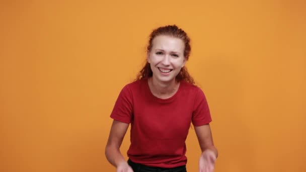 Mooie jonge dame in rood shirt die ogen bedekt met de hand, glimlacht, lacht — Stockvideo