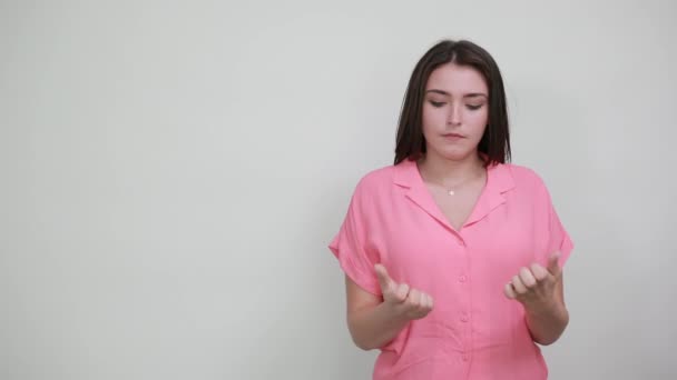 Atractiva joven mujer en camisa rosa mostrando las palmas de las manos en la cámara, mirando feliz — Vídeos de Stock