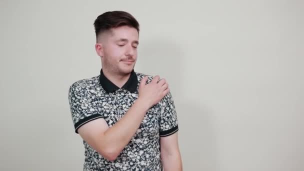 Красивий білий молодий чоловік тримає руки на плечі, біль — стокове відео