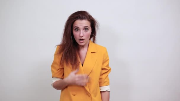 Confused young woman in yellow jacket looking directly, looking shocked — Stock Video