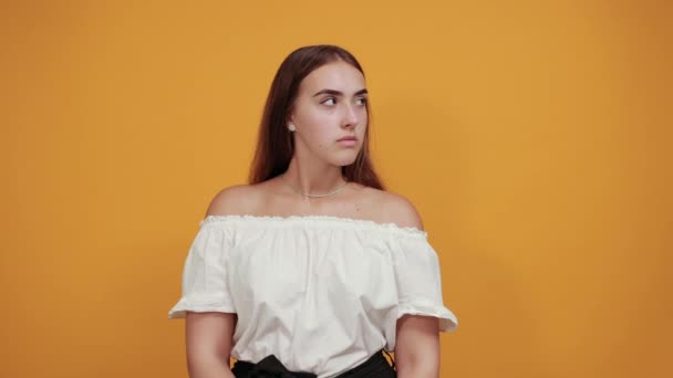 Attractive young woman keeping hand on ears, gossip concept on orange wall — Stock Video