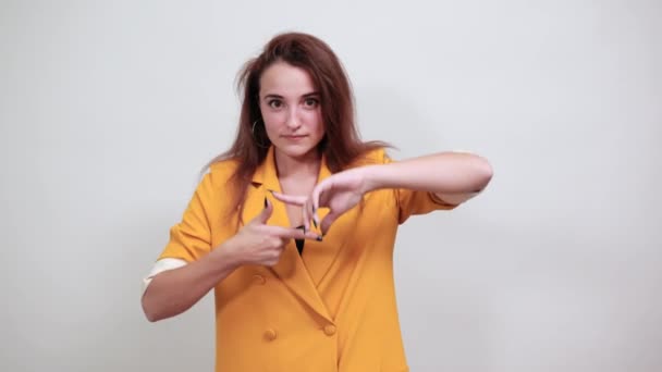 Wesoła młoda kobieta w żółtej kurtce robi gest ramki, uśmiecha się — Wideo stockowe