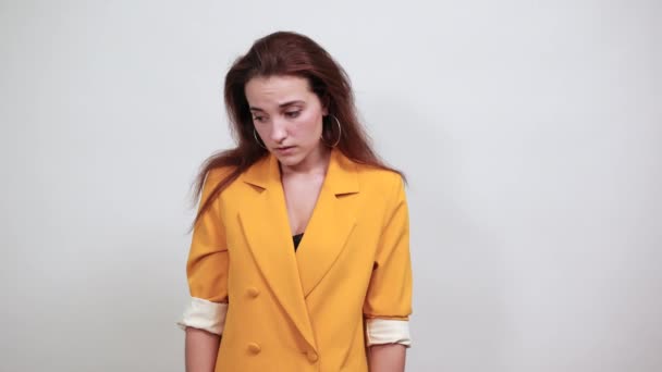 Attractive young woman in yellow jacket covering eyes with hands, looking sad — Stock Video