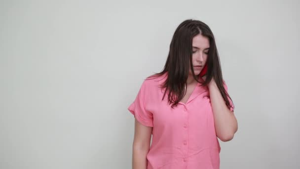 Donna attraente in camicia rosa che parla al telefono, indicando da parte . — Video Stock