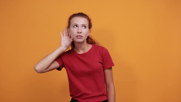 Atractiva joven dama de camisa roja con la mano en las orejas, chismes — Vídeos de Stock