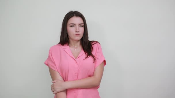 Σοκαρισμένη νεαρή γυναίκα με ροζ πουκάμισο κρατώντας τα χέρια στο στόμα, δείχνοντας φοβισμένη — Αρχείο Βίντεο