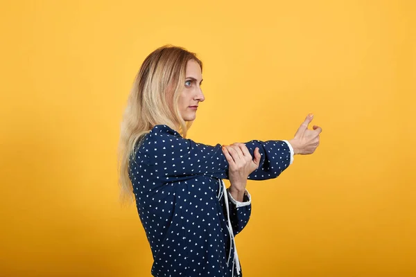 Allvarlig kaukasisk ung dam vistas i sidled, sträcker händerna över orange vägg — Stockfoto