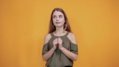 Güzel genç bayan göğsüne yumruk atıyor. Mutlu görünüyor, haki gömlek giyiyor.