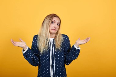 Hayal kırıklığına uğramış genç bir kadın şaşırmış görünüyor, ellerini turuncu duvarın üzerinden uzatıyor.