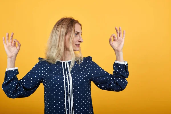 Charmig ung kvinna tittar åt sidan, gör okej gest över orange vägg — Stockfoto