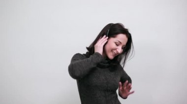 Gündelik siyah kazak giyen, müzik dinleyen, yardım eden, el kaldıran beyaz bir kadın.