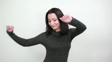 Moda siyah kazak giyen güzel bir kadın dans ediyor, yumruklarını havada tutuyor, geriniyor.