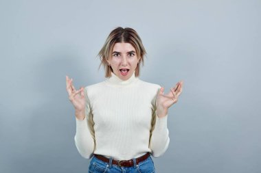 Sıradan giyinmiş korkmuş bir kadın yukarı bakıyor, el kaldırıyor, şok olmuş gibi.