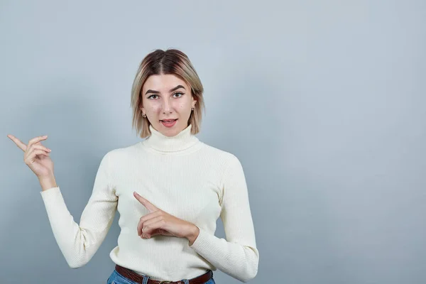 Schöne blonde junge Dame, die seinen Finger zur Seite zeigt — Stockfoto