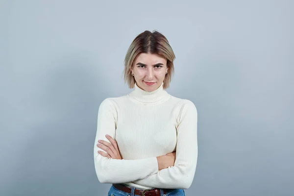 Sorridente giovane donna in casual maglione bianco che tiene le mani incrociate — Foto Stock