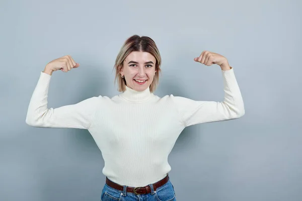 Kaukasiska flicka hålla händer, stoltsera sina muskler bär vit tröja — Stockfoto