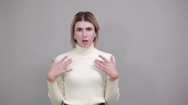 Ritratto di giovane donna sorridente in maglione pastello che mostra le dita sul petto — Video Stock