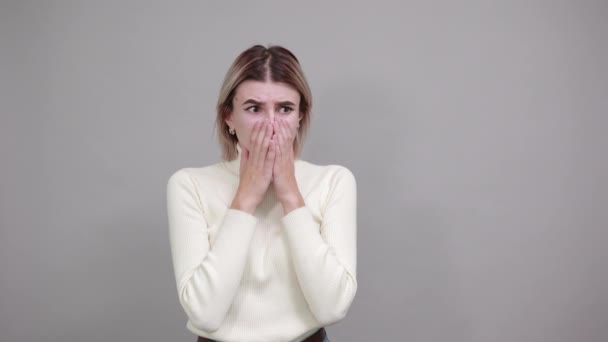 Nudná žena v neformálním oblečení, dívá se skrz prsty, s rukou za hlavou — Stock video