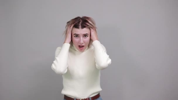Vacker kvinna i vardagskläder som tittar upp, reser sig på håret, som chockad — Stockvideo