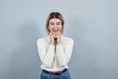 Genç, güzel, çekici bir kadın ellerini çenesinde tutuyor.