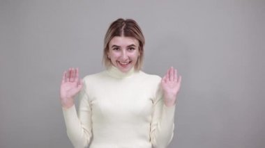 Gülümse, neşeli genç kadın, günlük gömlekle, kameraya bak, ellerini aç.