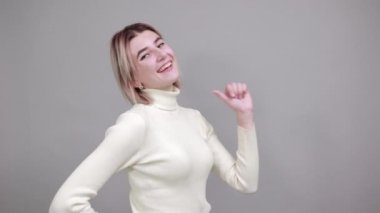 Genç beyaz kadın çok komik görünüyor. Kendini işaret ediyor, gülümsüyor.