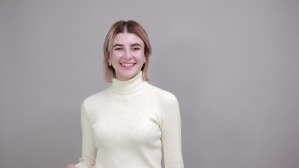 Aantrekkelijke jonge vrolijke vrouw in casual trui tonen op de werkplek — Stockvideo