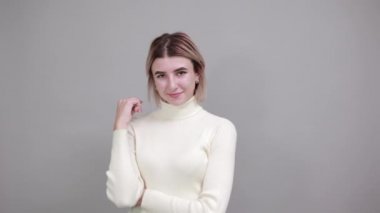 Boring young caucasian woman posing keeping hand on cheek. Greeting concept