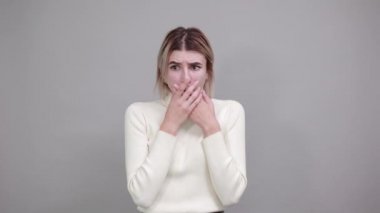 Ağzını kapatıp gülümseyen, elleri göğsünde olan genç bir kadın.