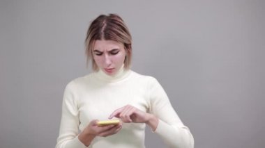 Harika genç bir kadın telefonu tutuyor, doğrudan bakıyor, elini işaret ediyor.