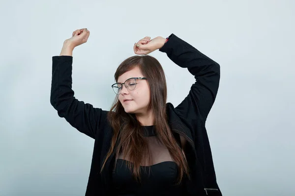 Женщина в обычной черной рубашке, смотрит в сторону, танцует жестом, держа руки вверх — стоковое фото