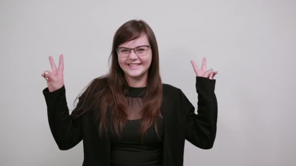 Hermosa mujer divertida sonriendo y mostrando signo de victoria aislado fondo gris — Vídeos de Stock