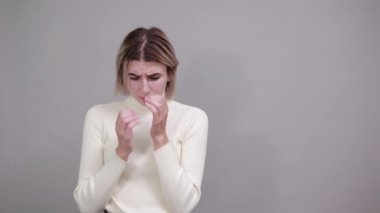 Şaşırtıcı yüz ifadesi olan genç sarışın kadın, elleriyle ağzını kapatıyor.