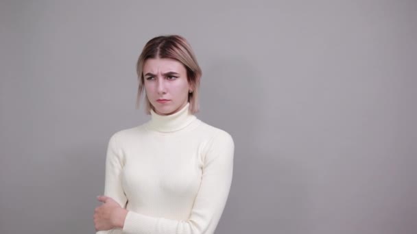 Retrato de una joven confundida mirando a un lado y cubriendo la barbilla con la mano — Vídeo de stock
