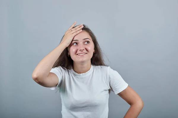 Flicka i vit t-shirt över isolerad grå vägg skrattar — Stockfoto