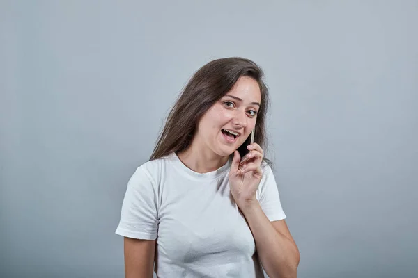 Meisje praat aan de telefoon en kijkt ons aan met een mysterie — Stockfoto