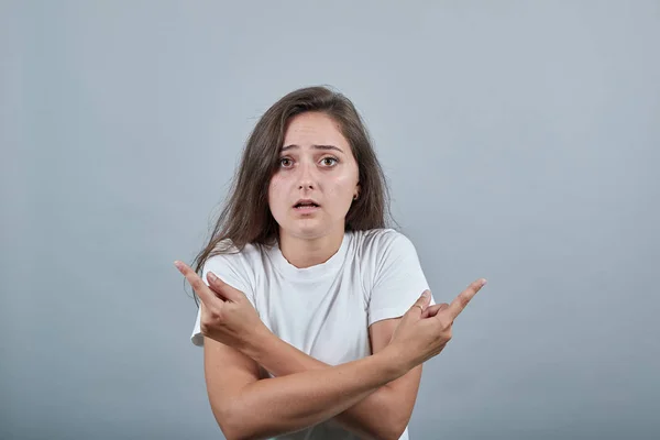 Señora en camiseta blanca sobre la pared gris señalando los dedos en diferentes direcciones — Foto de Stock