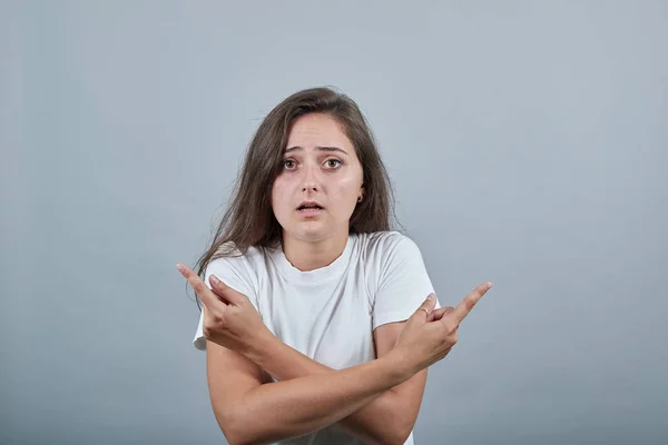 Dam i vit t-shirt över grå vägg pekar finger i olika riktningar — Stockfoto