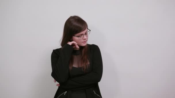 Удивленная женщина в случайном черном платье, смотрит вниз, держа руку в волосах — стоковое видео
