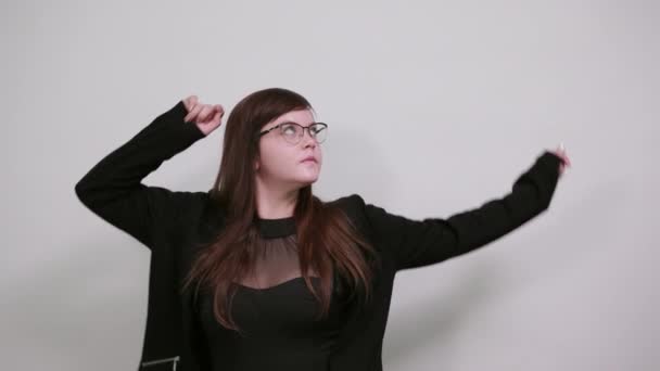 Mosolygó fiatal nő alkalmi fekete ruhában, félrenéz, feltartott kézzel — Stock videók