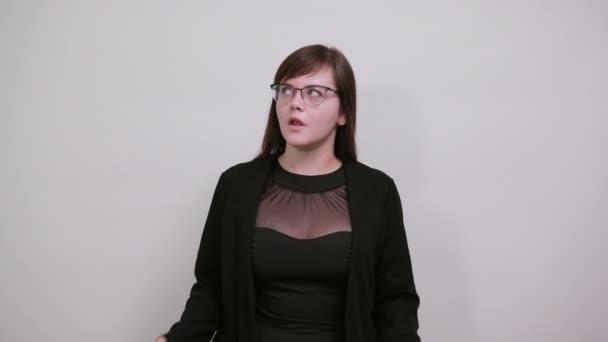 Шокированная веселая молодая женщина в черной рубашке, смотрящая в камеру, расправляя руки — стоковое видео
