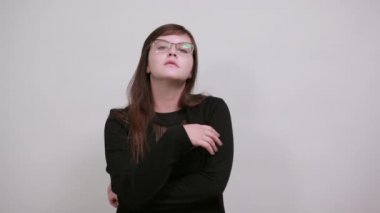 Kadının yandan görünüşü, gülümsemesi, ellerini çenesinde tutması, güzel gözlükleri olması.