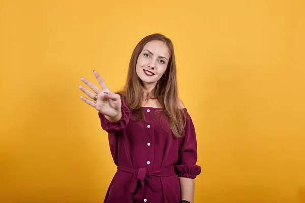 Mujer joven sobre aislada pared naranja contando cuatro con los dedos y sonriendo —  Fotos de Stock