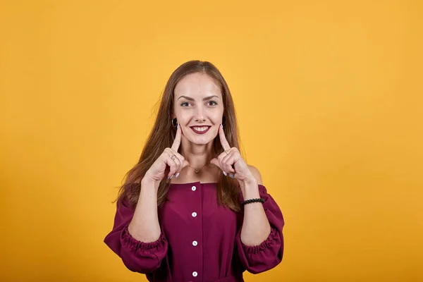 Mujer joven muestra su sonrisa con los dedos —  Fotos de Stock