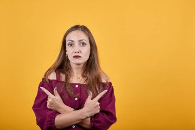 Burgonyalı kadın turuncu duvarın üzerinden farklı yönleri işaret ediyor.