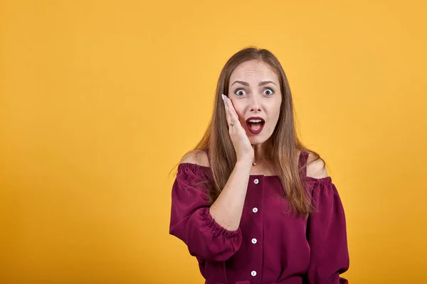 Mujer joven en blusa borgoña con sorpresa y expresión facial impactada — Foto de Stock