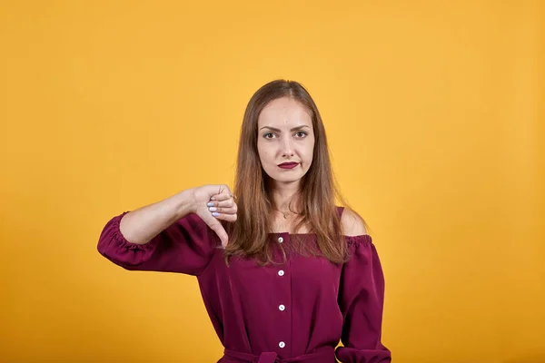 Женщина показывает знак вниз большого пальца с недовольным взглядом — стоковое фото