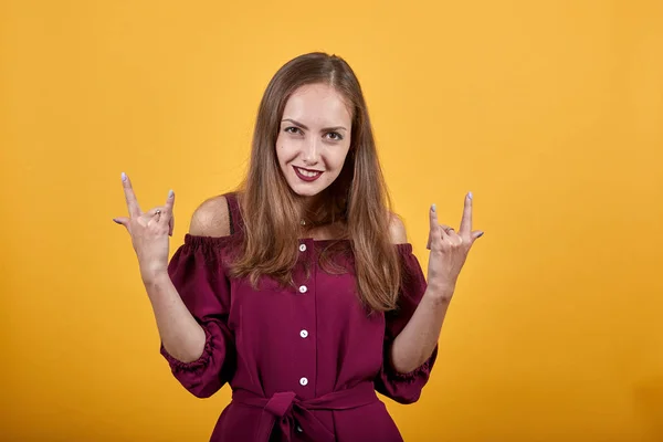 Молодая женщина делает рок-жест с улыбкой на лице — стоковое фото