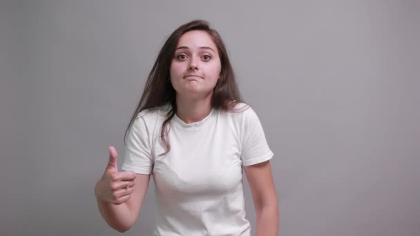Приваблива біла молода жінка робить нормальний жест, посміхаючись . — стокове відео